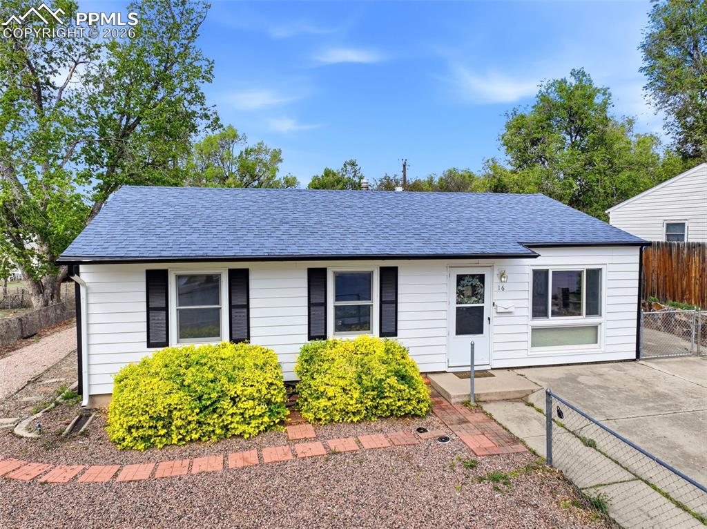 Image 31 of 38: White siding exterior with a blue shingle roof, black window shutters, and 