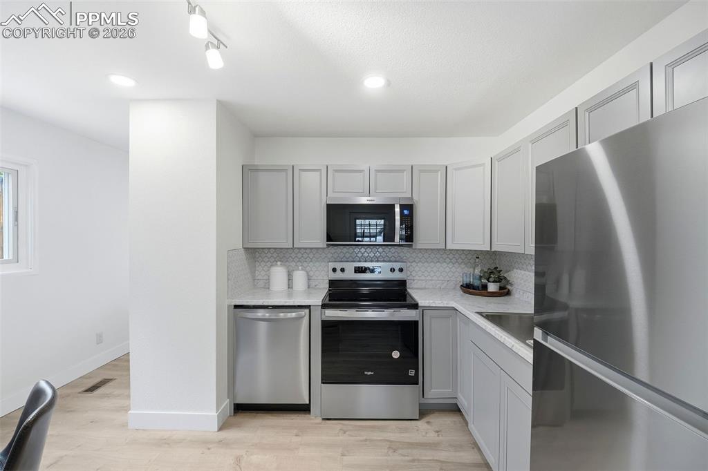 Image 7 of 38: Modern kitchen featuring light gray cabinetry, stainless steel appliances, 