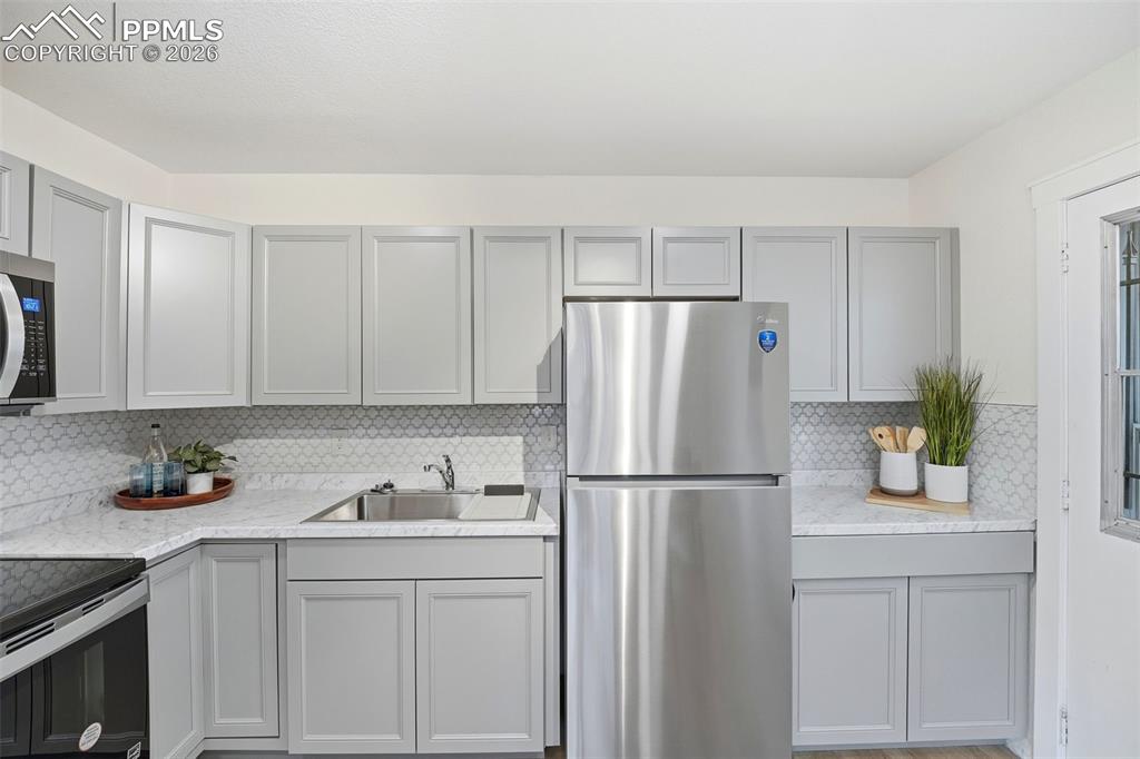 Image 8 of 38: Modern kitchen featuring grey shaker-style cabinetry, stainless steel appli