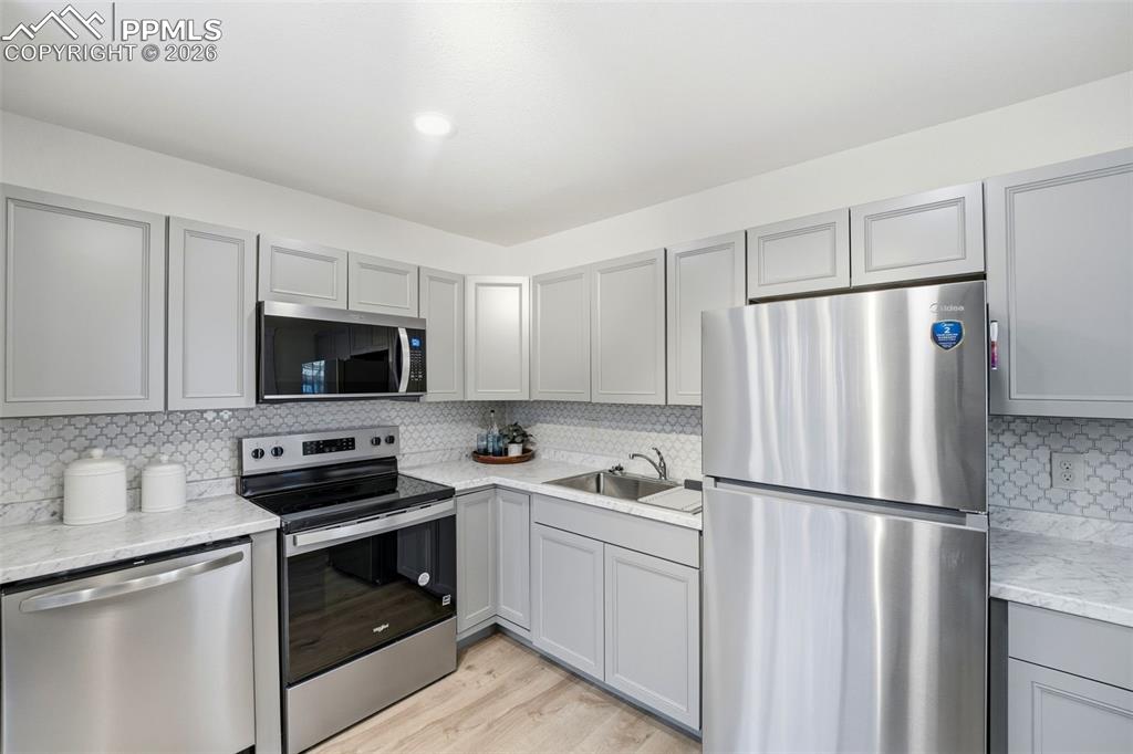 Image 9 of 38: Kitchen featuring stainless steel appliances, light gray cabinetry, white m