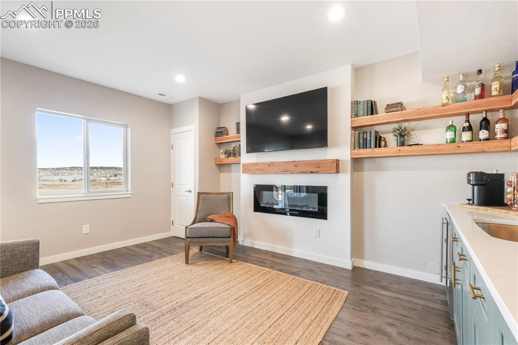 Image 37 of 50: Walk out basement family room with electric fireplace and wet bar with quar