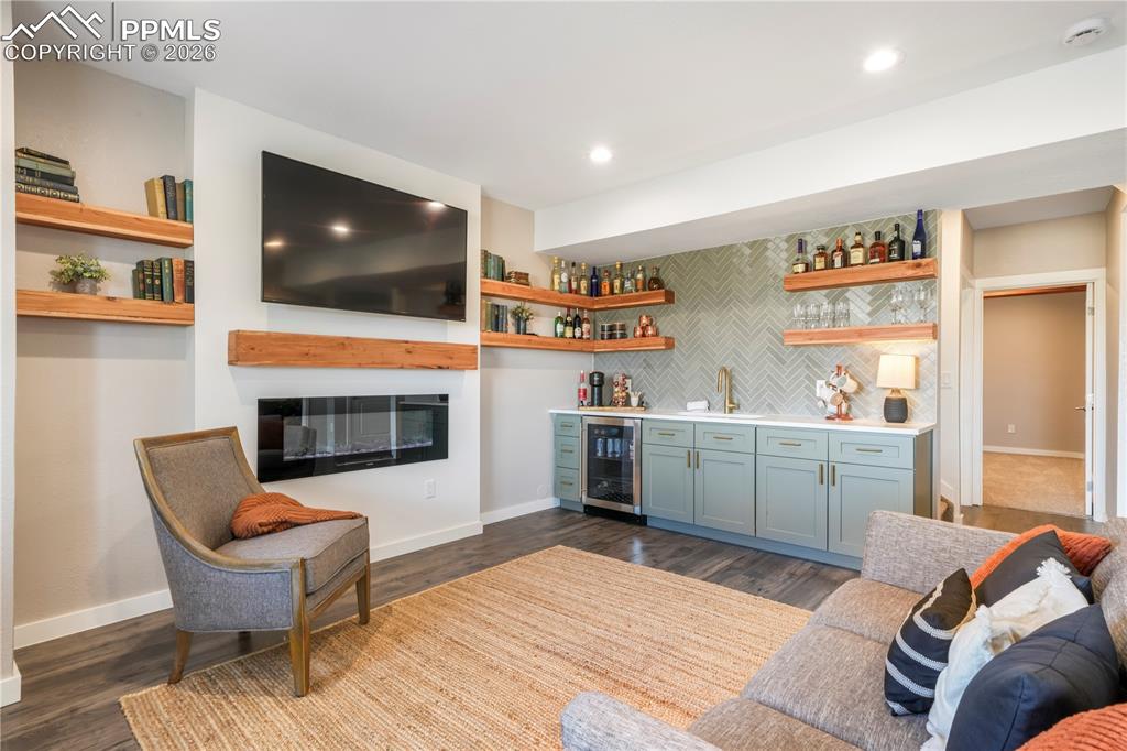 Image 39 of 50: Walk out basement family room with electric fireplace and wet bar with quar