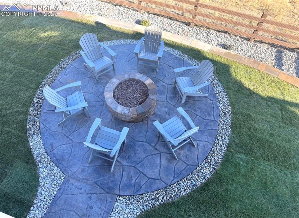 Image 46 of 50: Backyard with gas firepit, fenced yard, tiered stamp concrete patio areas a