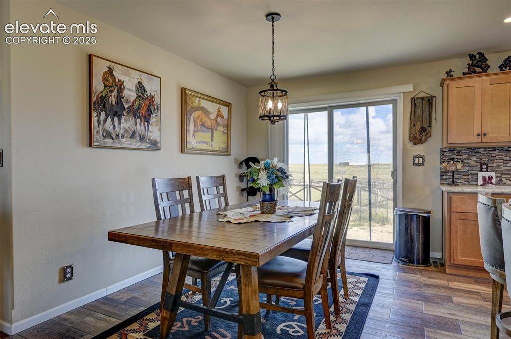 Image 14 of 50: Dining area with wood-finish flooring, a contemporary chandelier, and slidi