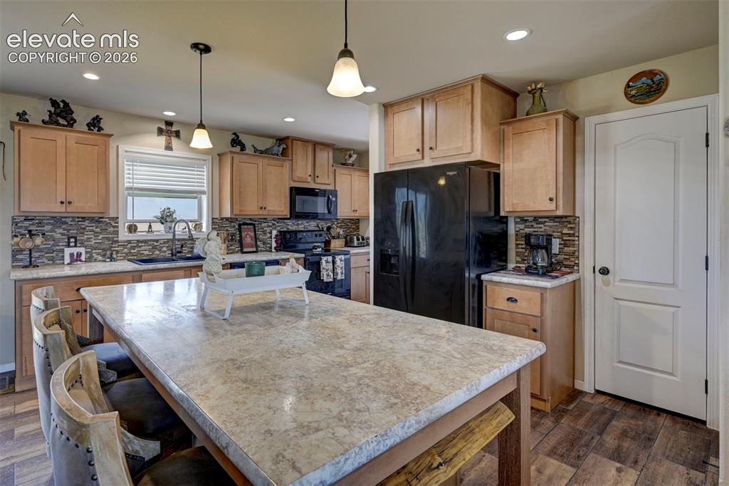 Image 15 of 50: Kitchen featuring wood-finish cabinetry, stone-look countertops, a mosaic t