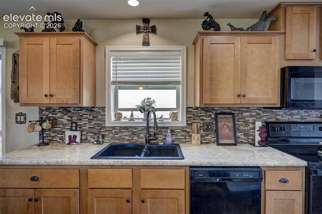 Image 17 of 50: Wood-finish cabinetry paired with a mosaic tile backsplash