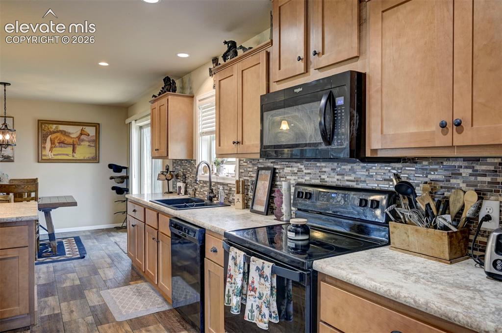 Image 22 of 50: Wood-finish plank flooring, wood cabinetry, stone-look countertops, full ti