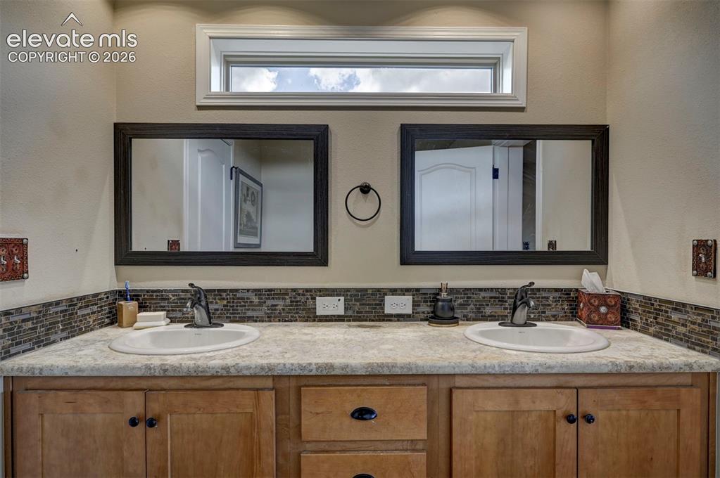 Image 29 of 50: Double vanity with integrated sinks, wood-finish cabinetry, and framed mirr