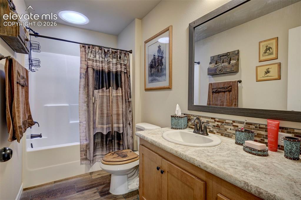 Image 30 of 50: Bathroom featuring a white bathtub/shower combination, wood-finish flooring