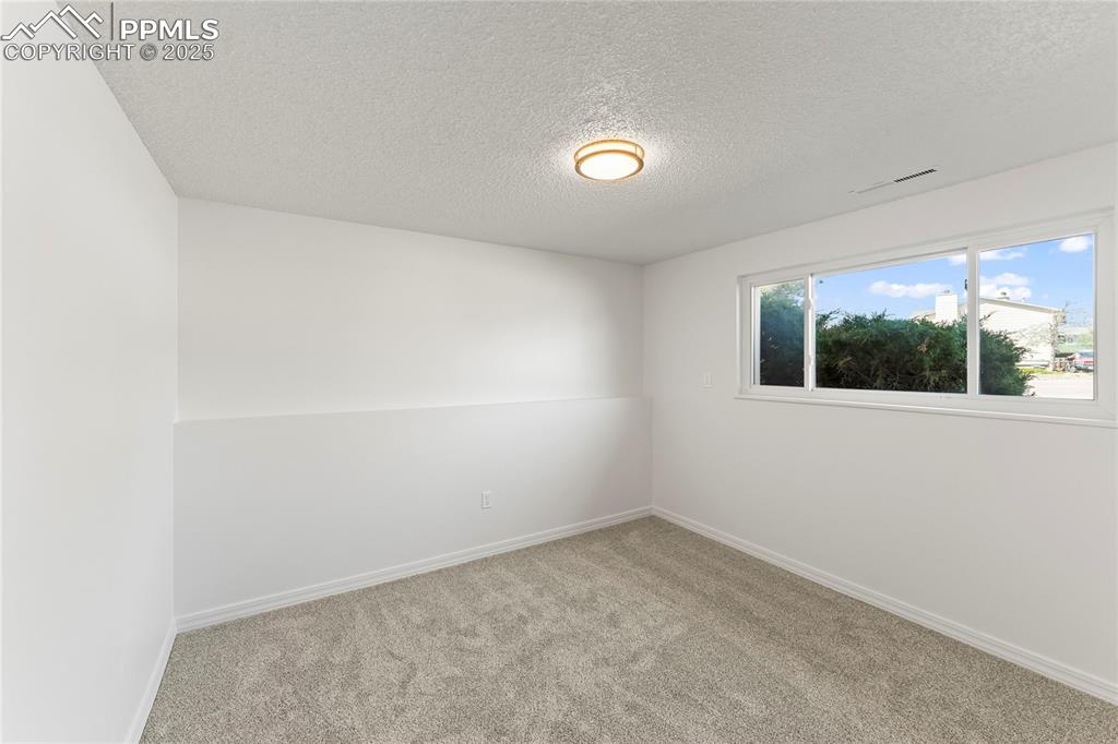 Image 13 of 19: Carpeted spare room featuring baseboards and a textured ceiling