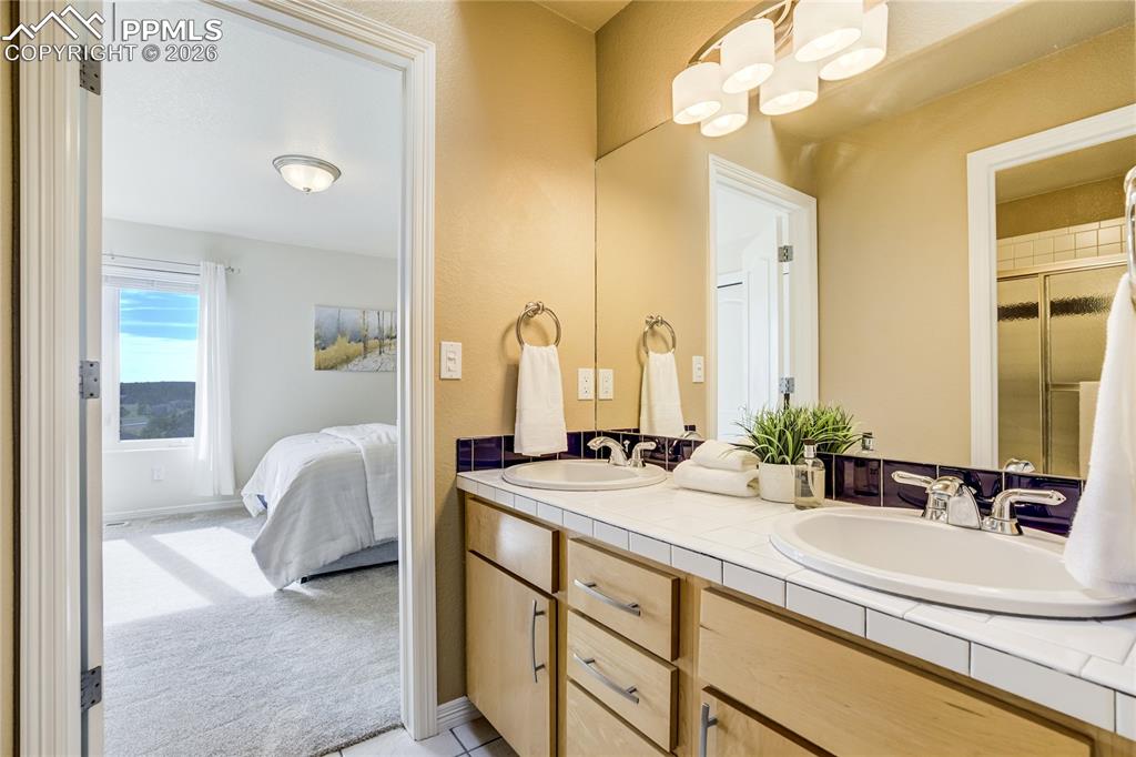 Image 37 of 50: Jack-and-Jill full bath with dual sinks and a skylight that brings in natur
