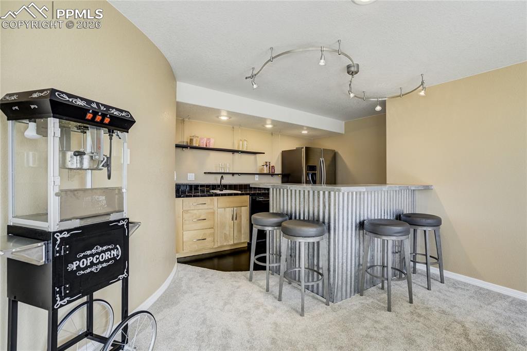 Image 44 of 50: Well-appointed wet bar with full-size refrigerator and dishwasher, creating