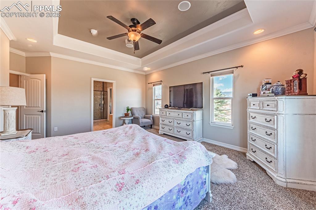 Image 11 of 36: Bedroom featuring light colored carpet, baseboards, crown molding, and a tr