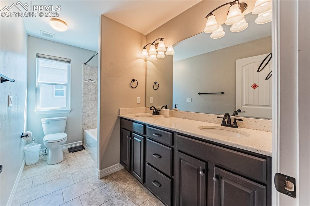 Image 13 of 36: Full bath with double vanity, visible vents, toilet, and a sink