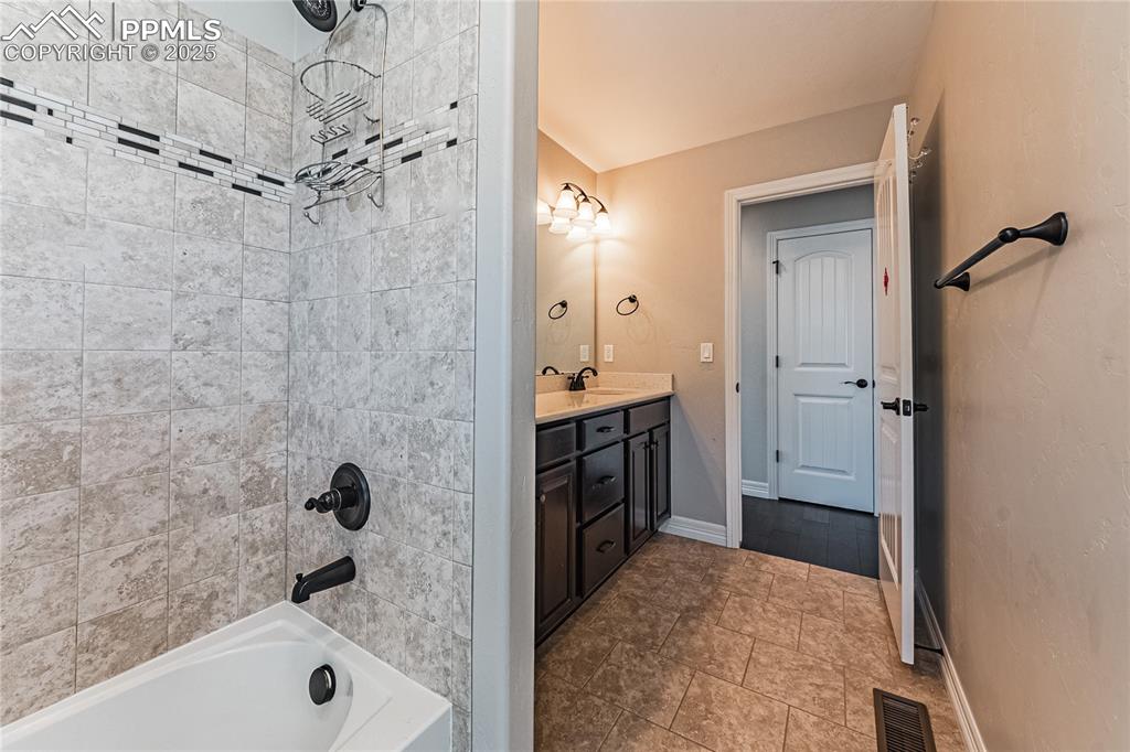 Image 18 of 36: Full bath with visible vents, a sink, double vanity, baseboards, and bathtu