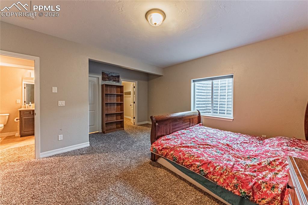 Image 26 of 36: Carpeted bedroom with connected bathroom, baseboards, and a spacious closet