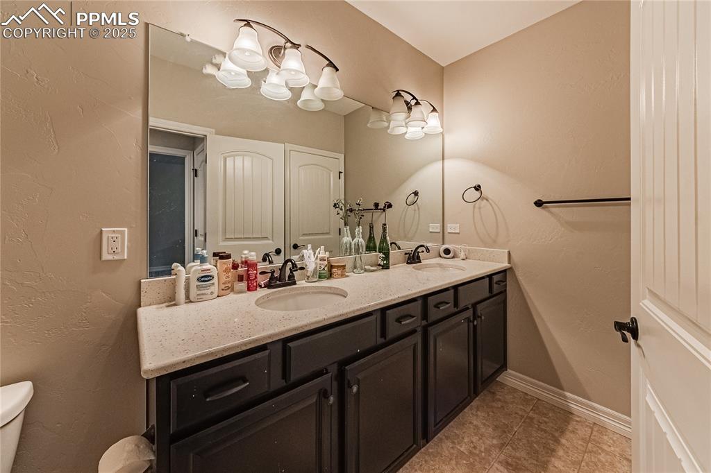 Image 29 of 36: Bathroom with a sink, baseboards, toilet, and double vanity