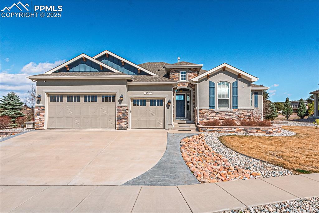 Image 36 of 36: View of front of home featuring stone siding, a garage, driveway, and stucc