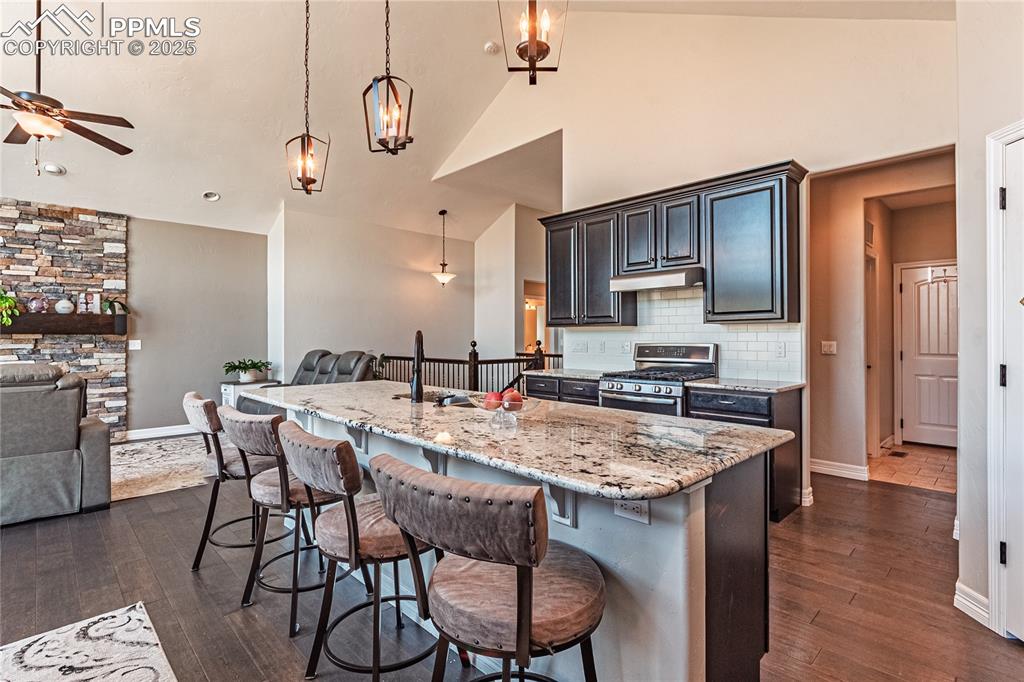 Image 4 of 36: Kitchen featuring under cabinet range hood, stainless steel gas stove, open