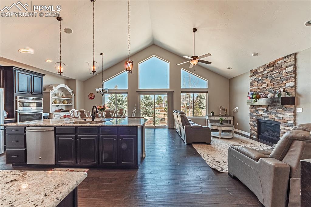 Image 5 of 36: Kitchen with dark wood-type flooring, ceiling fan, open floor plan, a stone