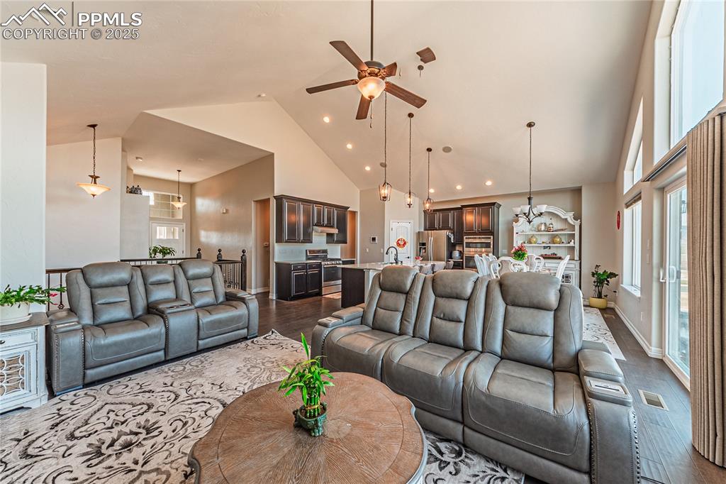 Image 6 of 36: Living area with baseboards, visible vents, high vaulted ceiling, dark wood