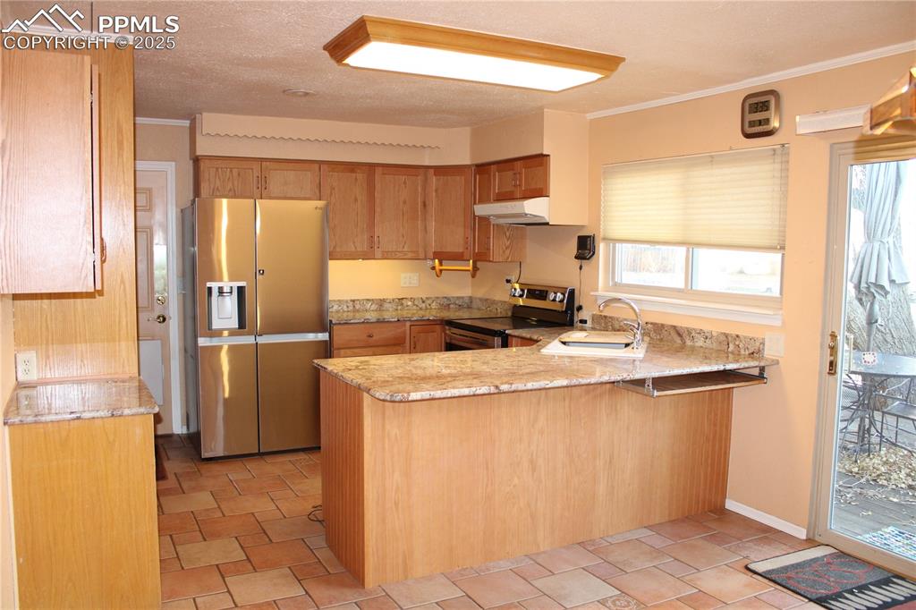 Image 15 of 48: Kitchen with stainless steel appliances, a peninsula, crown molding, light