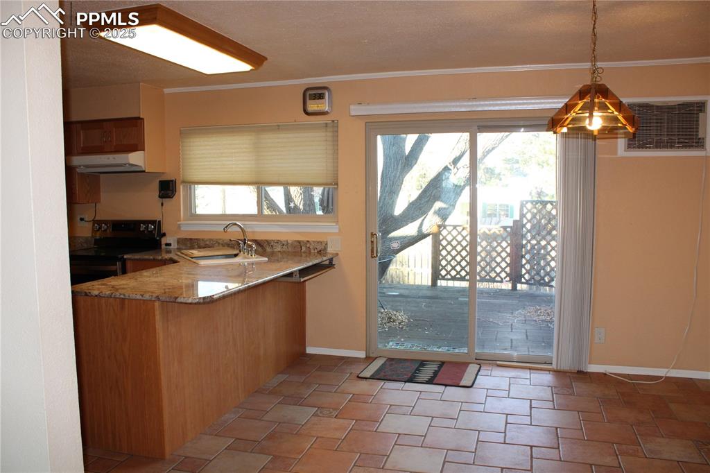 Image 19 of 48: Kitchen with electric stove, light stone counters, pendant lighting, under
