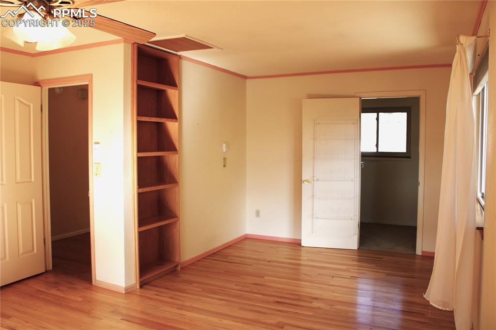 Image 21 of 48: Primary bedroom featuring hardwood floors, built-ins, walk-in closet.