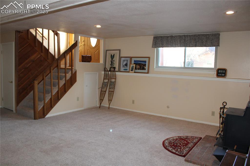Image 37 of 48: Family room with a wood stove, carpet, stairway, and recessed lighting