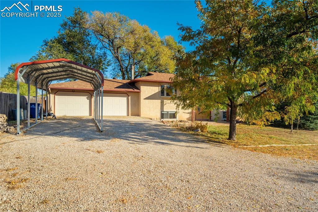 Image 40 of 48: View of front of property with driveway, stucco siding, and a carport