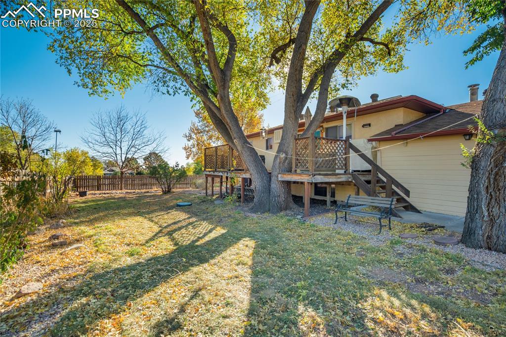 Image 44 of 48: Fenced backyard with stairs and a wooden deck