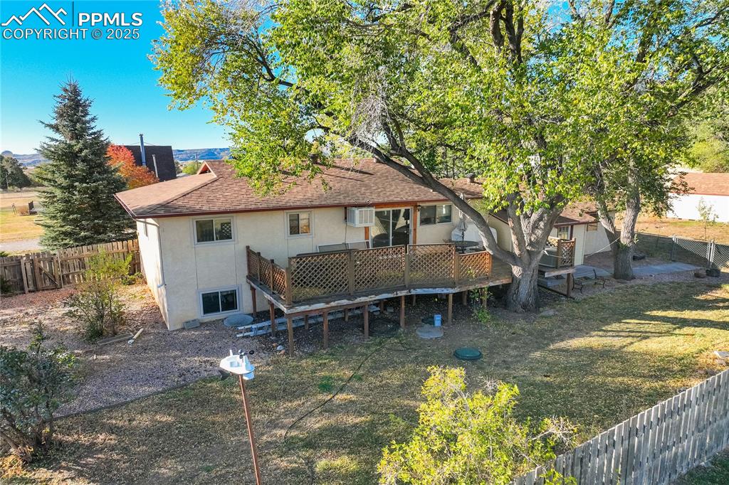 Image 46 of 48: Back of house featuring a fenced backyard, a deck, stucco siding, and roof 