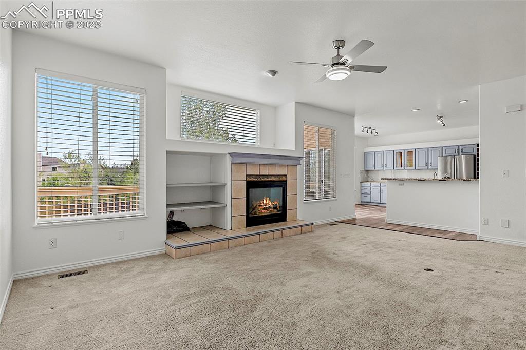Image 13 of 48: Unfurnished living room featuring carpet, ceiling fan, baseboards, and a ti