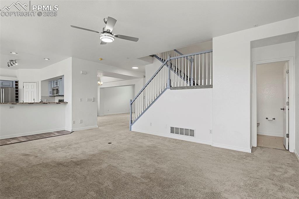 Image 14 of 48: Unfurnished living room featuring carpet flooring, a ceiling fan, baseboard
