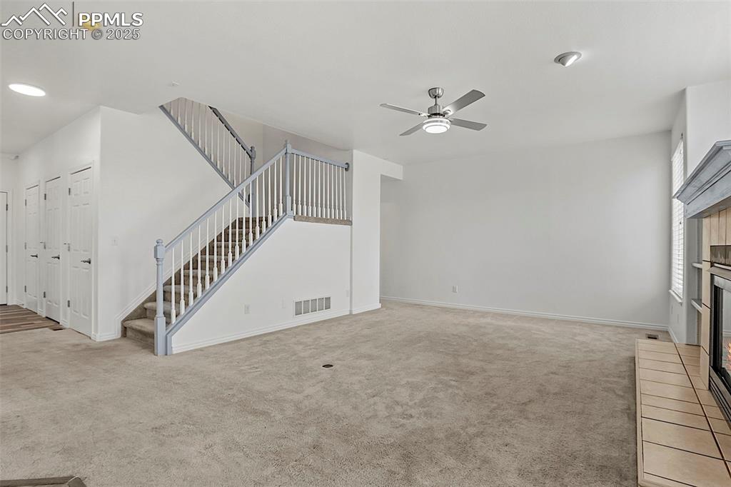 Image 15 of 48: Unfurnished living room featuring a fireplace, carpet floors, stairway, a c