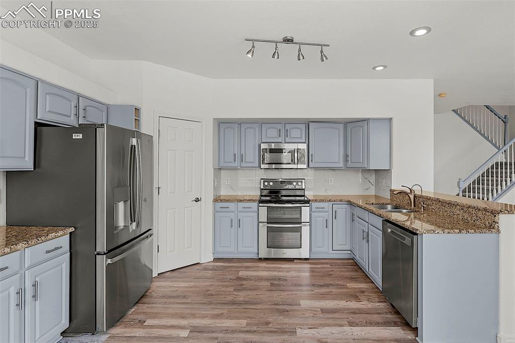 Image 18 of 48: Kitchen featuring appliances with stainless steel finishes, a sink, wood fi