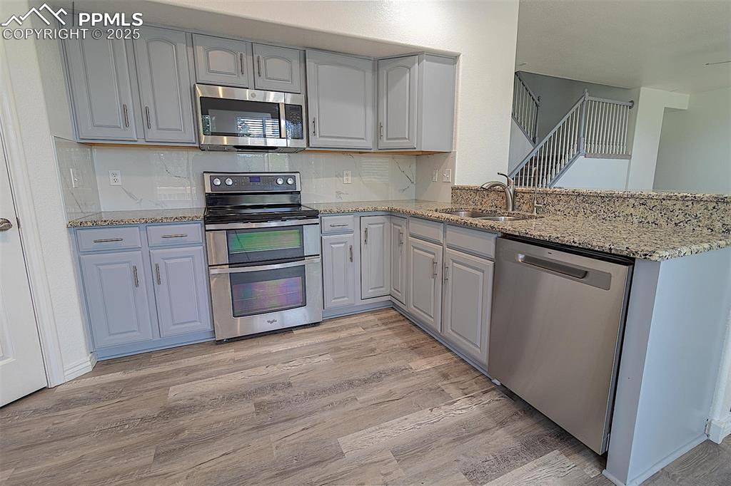Image 19 of 48: Kitchen with appliances with stainless steel finishes, a sink, light wood-s