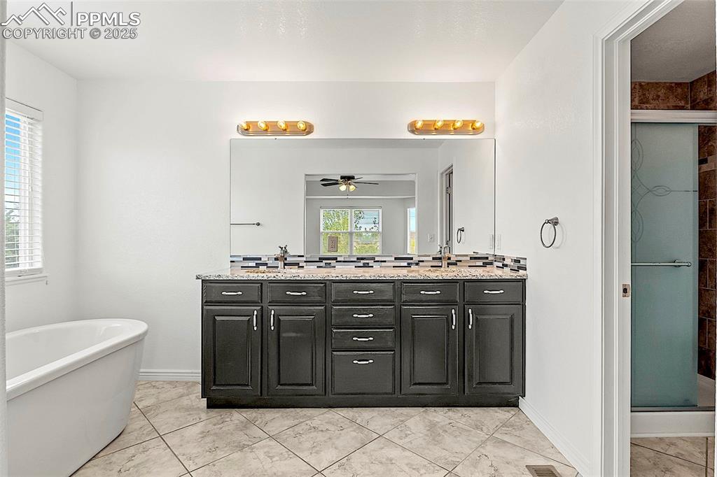 Image 28 of 48: Full bath featuring a ceiling fan, a shower stall, double vanity, a freesta