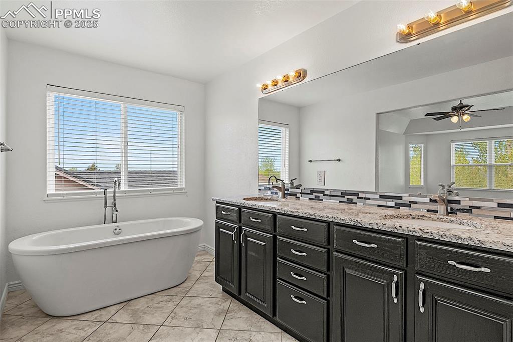 Image 29 of 48: Full bath with double vanity, a ceiling fan, a freestanding tub, and tastef