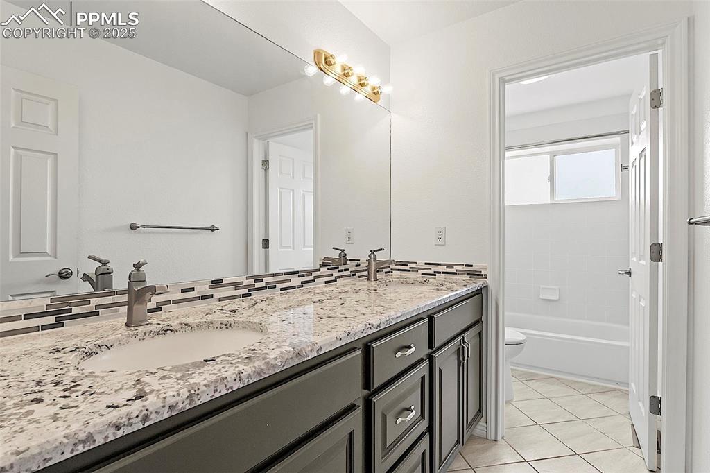 Image 32 of 48: Full bath with toilet, double vanity, and tile patterned flooring