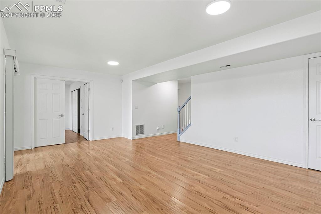 Image 37 of 48: Unfurnished living room with stairs, light wood-style floors, baseboards, a
