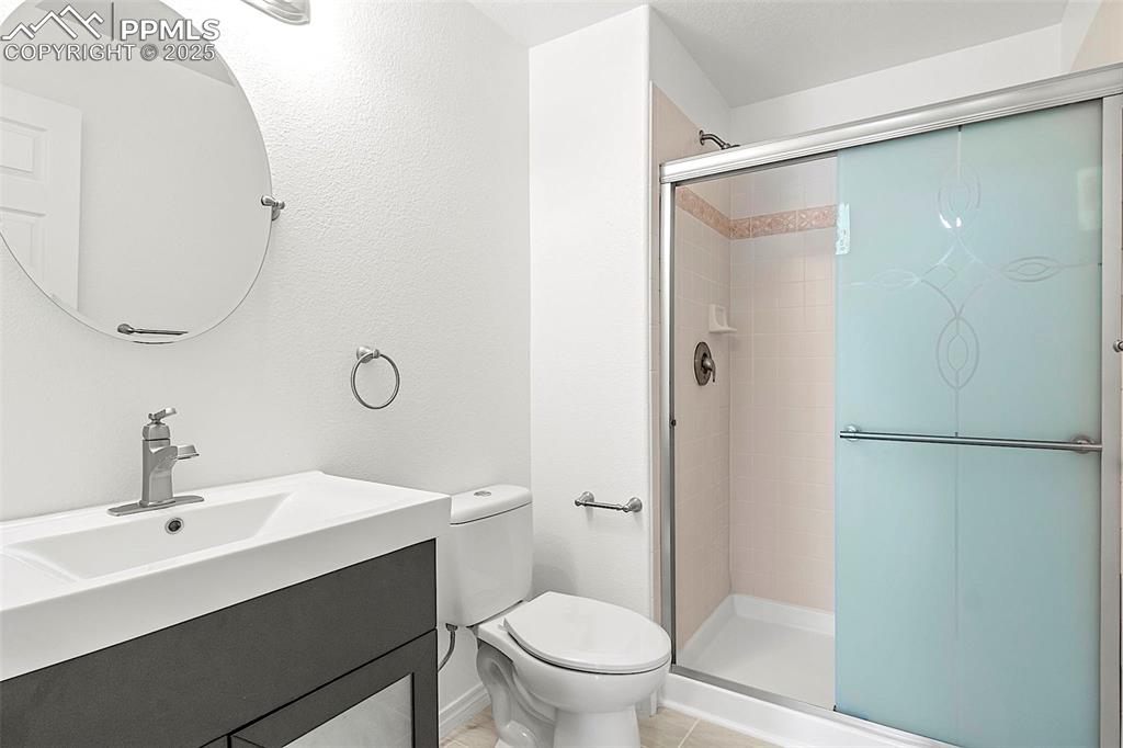 Image 40 of 48: Full bathroom featuring toilet, a stall shower, vanity, and tile patterned 