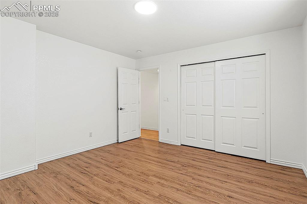 Image 42 of 48: Unfurnished bedroom with light wood-style flooring, baseboards, and a close