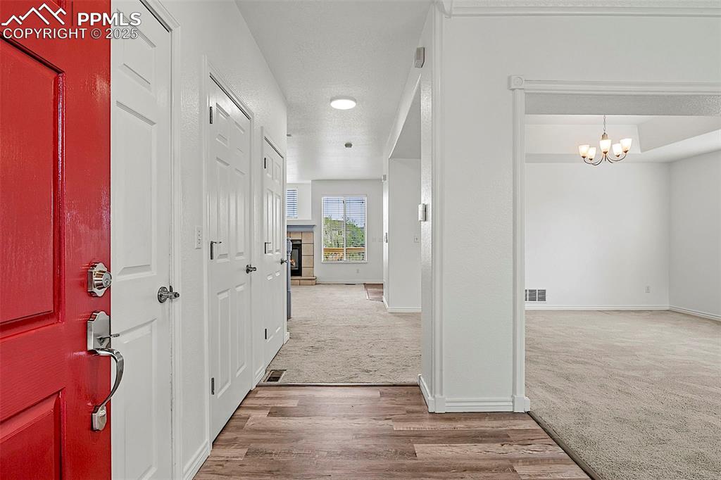 Image 8 of 48: Hall featuring carpet, baseboards, a chandelier, and wood finished floors