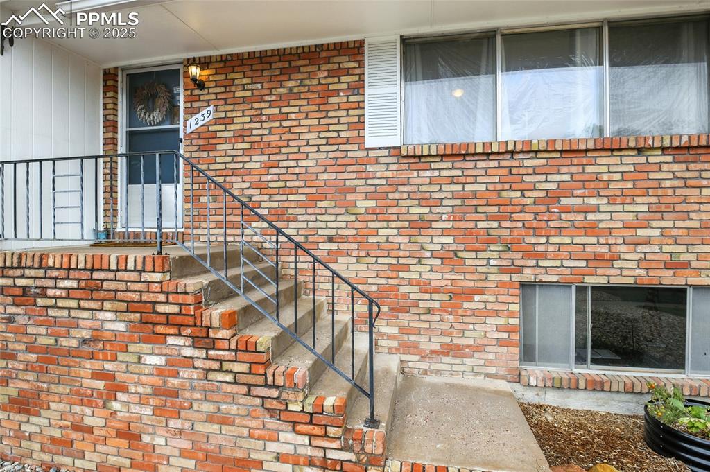 Image 4 of 35: Doorway to property featuring brick siding