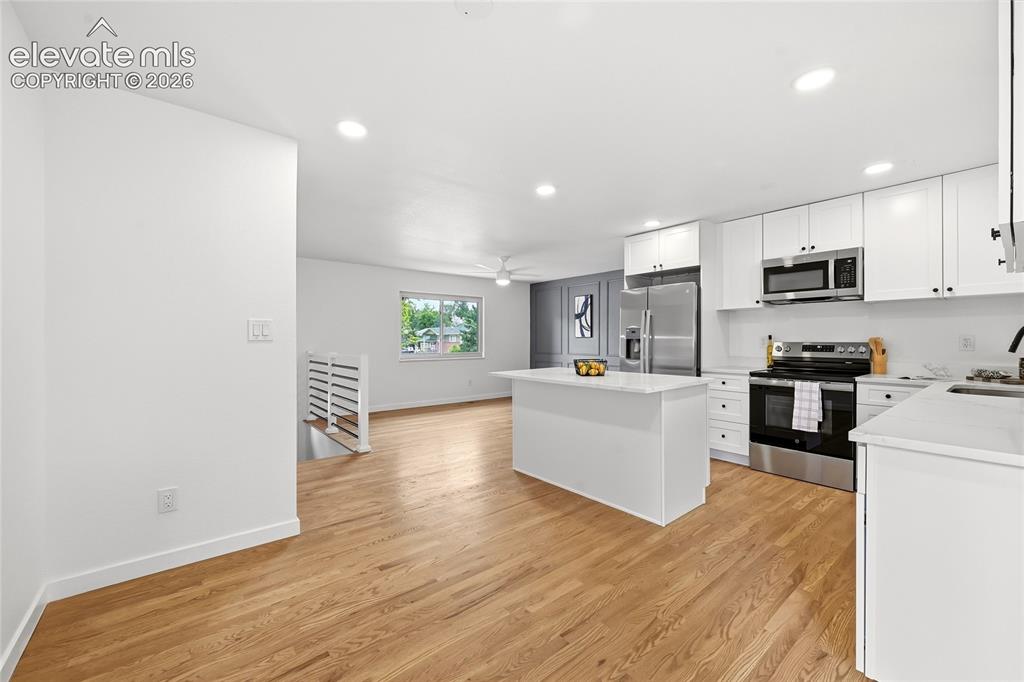 Image 10 of 30: Open-concept living area featuring wood-finish flooring, recessed lighting,