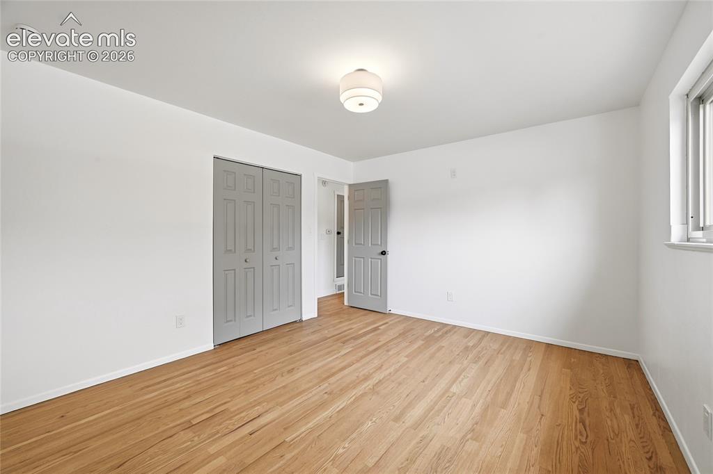 Image 12 of 30: Spacious room featuring wood-finish flooring, white walls, and a ceiling-mo