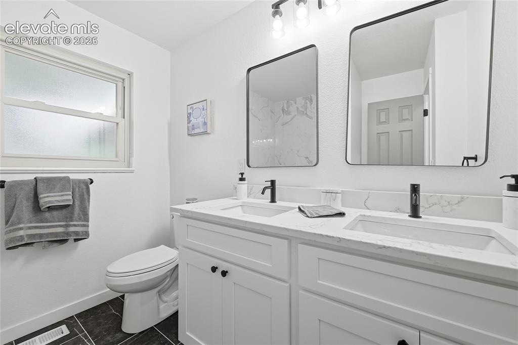 Image 13 of 30: Double vanity featuring white shaker-style cabinetry with matte black hardw
