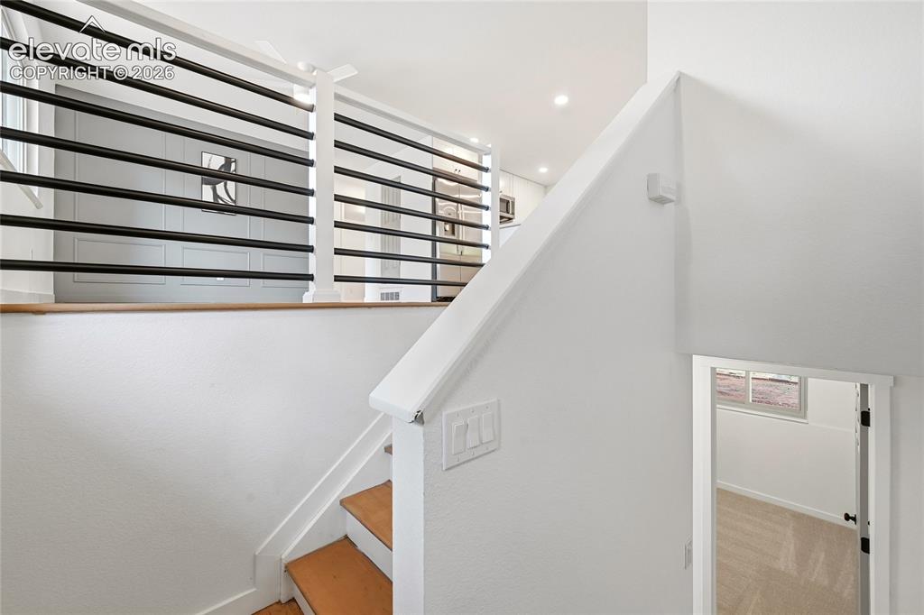 Image 17 of 30: Staircase featuring wood treads and white risers, complemented by a contemp