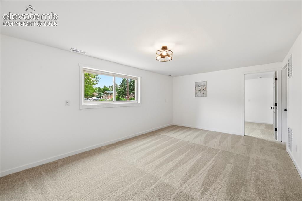 Image 18 of 30: Spacious room featuring neutral carpeting, white walls, a multi-pane window